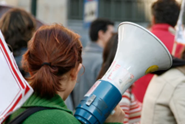 Young people demonstrate on the street with placards and megaphones.