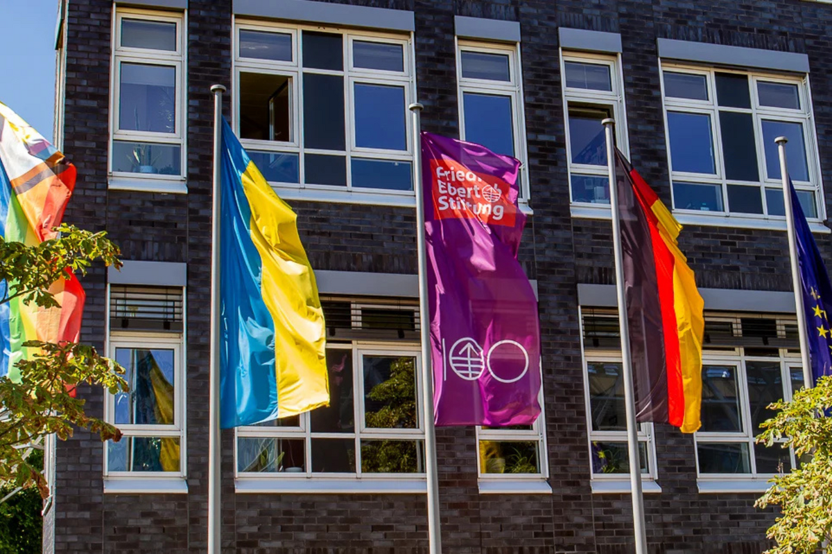 An array of flags in front of the Berlin HQ of the Friedrich-Ebert-Stiftung. The German and EU flag next to the Ukrainian flag, the rainbow flag and the FES 100 jubilee flag.