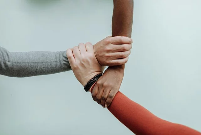 Hands together before a white background.