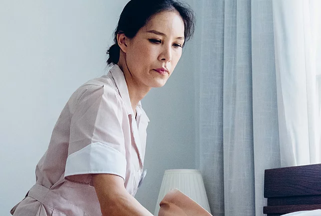 A housekeeper makes a bed.