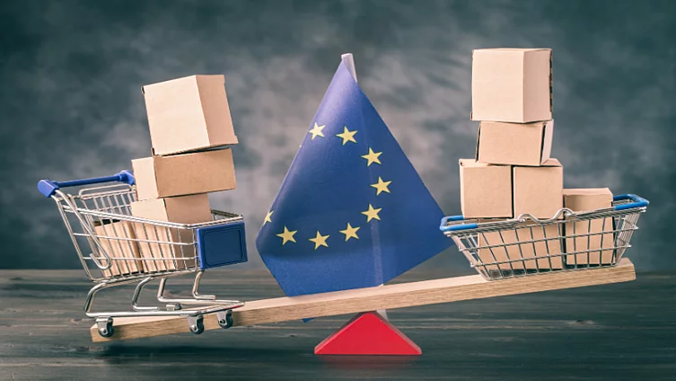 A scale with an EU flag tipping between two shopping carts.