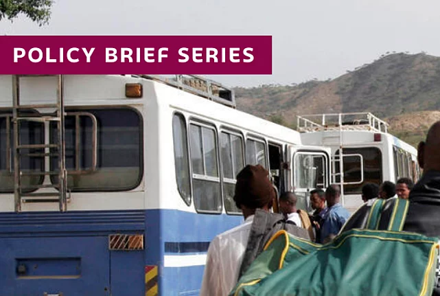 Repatriation of 232 Ethiopians across the Mereb Bridge: People with luggage waiting between busses and a blue UN sign.