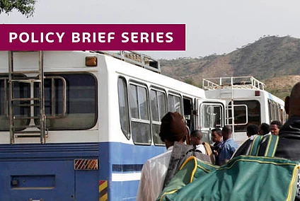 Repatriation of 232 Ethiopians across the Mereb Bridge: People with luggage waiting between busses and a blue UN sign.