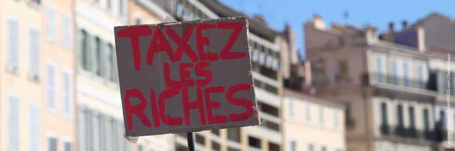 A protester holding up a sign reading "Taxez les Riches" during a demonstration in Marseille.