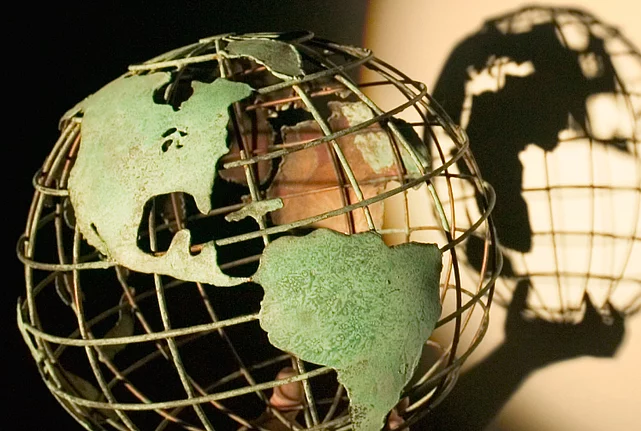 A model of a globe casting a shadow on the wall behind it.